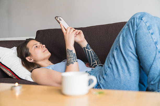 istock Young woman relaxing on sofa using smartphone at home 2218073517