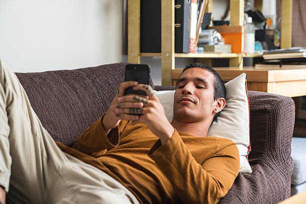 istock Young man relaxing on sofa using smartphone at home 2218073691