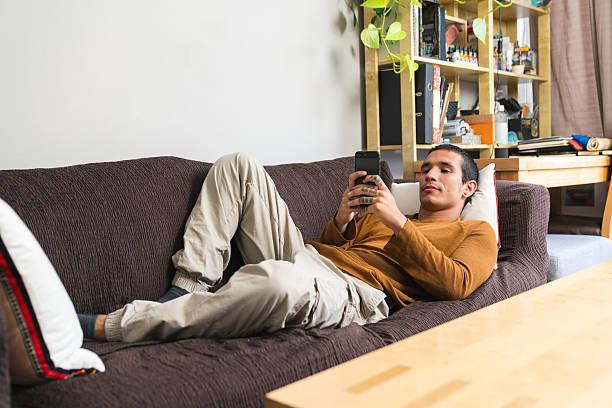 istock Young man relaxing on sofa using smartphone at home 2218073711