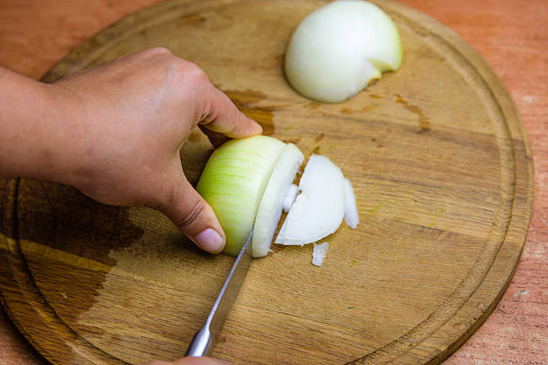 istock Woman cutting white onion on cutting board 2218079779