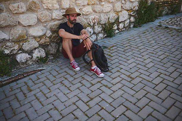 istock Traveler Taking a Break Against a Stone Wall in a Sunny Urban Setting 2218081396