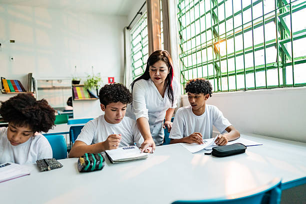 istock Mature teacher assisting students during class at school 2218081611