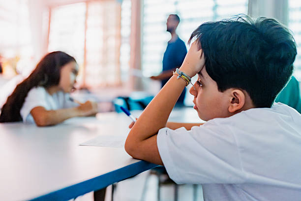 istock Bored schoolboy studying in the classroom at school 2218083362