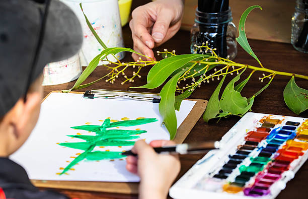 Child painting eucalyptus leaf with watercolors during nature art activity