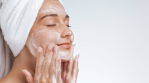 istock Relaxed Woman with Towel Gently Cleansing Face with Foaming Soap 2218090838