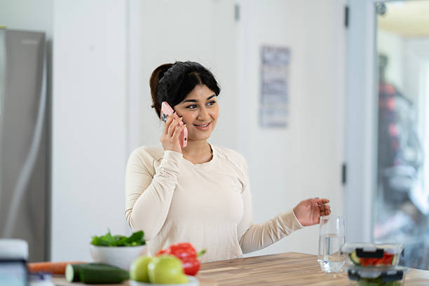 istock Woman Smiling While Talking on Mobile Phone in a Bright Kitchen Setting 2218091766