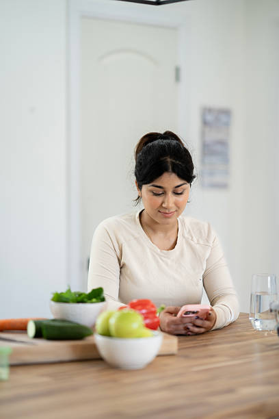 istock Woman Using Smartphone While Preparing Healthy Meals in a Bright Kitchen 2218091818
