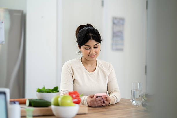 istock Woman Enjoying Smartphone in Modern Kitchen While Surrounded by Fresh Produce 2218092031