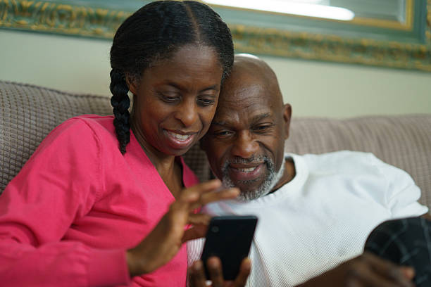 istock Smiling Mature Couple Using a Phone Together While Relaxing at Home 2218093856