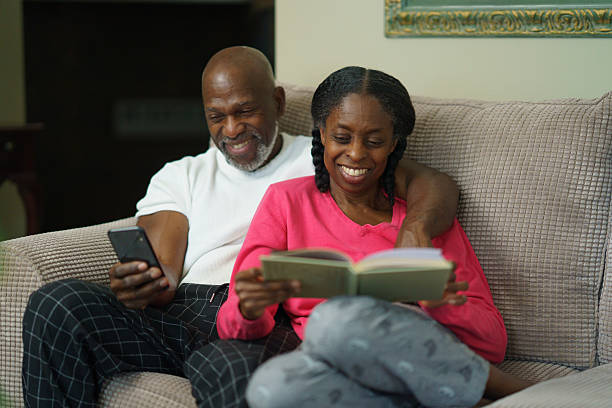 istock Happy Couple Reading and Using a Smartphone Relaxing on a Cosy Sofa 2218094314