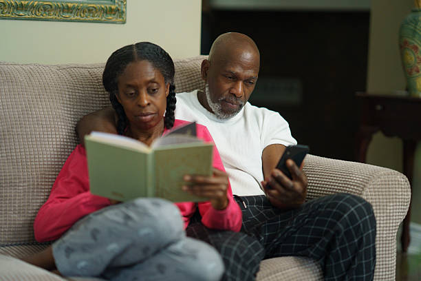 istock Couple Relaxing on Couch Reading and Using Mobile Phone Together 2218094354