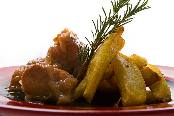 A mouthwatering close-up of a comforting dish featuring tender, slow-braised chicken in a rich onion sauce, paired with golden, crispy potato wedges and garnished with a sprig of fresh rosemary. This image captures the essence of homemade elegance, blending traditional flavors with a sophisticated plating style. Ideal for food blogs, recipe collections, restaurant menus, or editorial content highlighting authentic, hearty meals with a gourmet touch. The dramatic lighting and clean white background emphasize the texture and richness of the dish, making it visually irresistible.