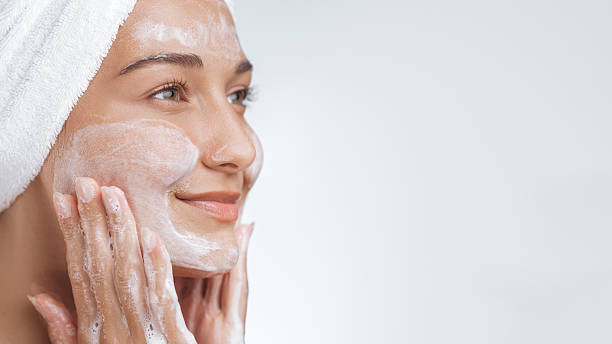 istock Smiling Woman Gently Cleansing Face with Foaming Soap During Skincare Routine 2218095855