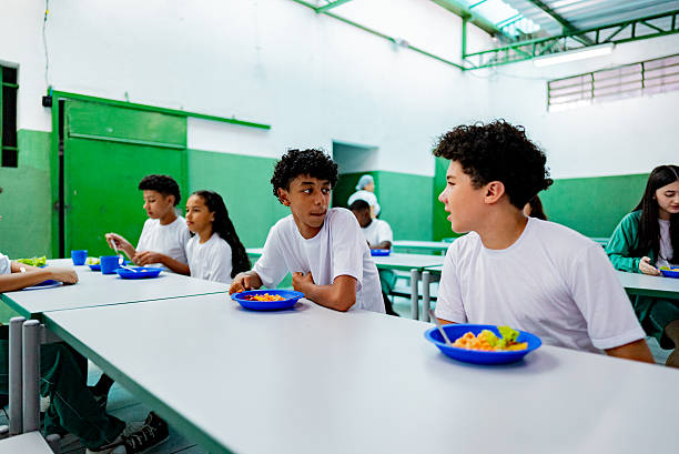 istock Schoolboys talking and having lunch in the cafeteria at school 2218098684