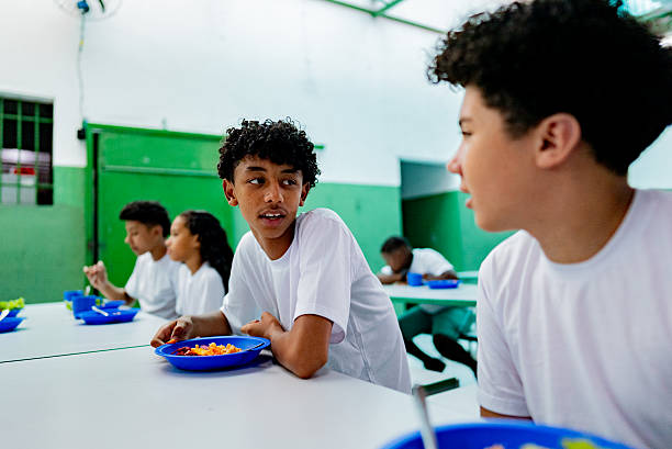 istock Schoolboys talking and having lunch in the cafeteria at school 2218098696