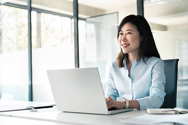 istock Thoughtful 30s middle-aged woman using computer for financial bank work online. Mature Asian professional specialist businesswoman working on laptop pc sitting at desk in office looking dreaming aside 2218098855