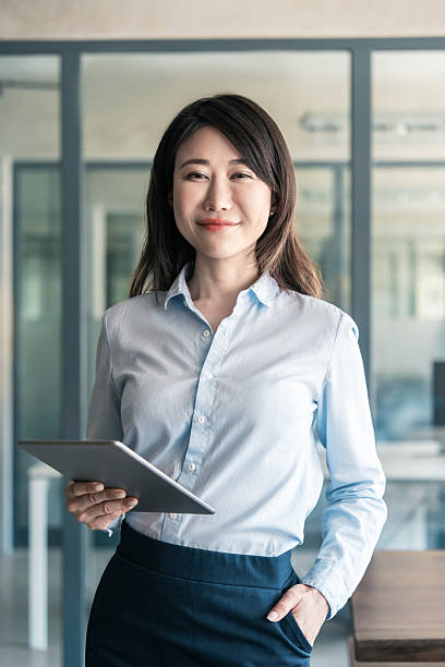 istock Asian mature woman ceo analyst manager using tablet for business work. Smiling entrepreneur businesswoman leader in formal clothes holding touchscreen pc device in office. Vertical portrait at camera 2218098873