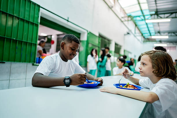 istock Schoolboys talking and having lunch in the cafeteria at school 2218099082
