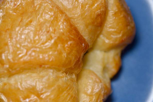 Savory ham and cheese croissant cut in half showing soft layers.