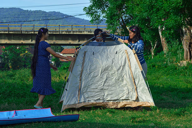 istock Girls begin setting up camping tent on open grass 2218102984