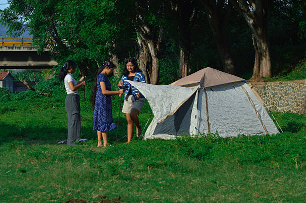 istock Girls working on adding canopy cloth to camping tent 2218103056