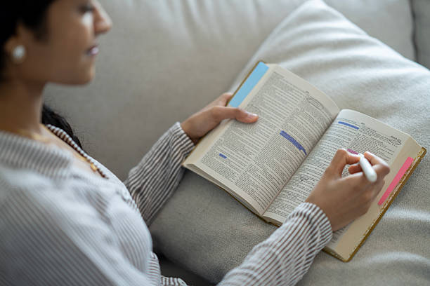 Young Woman Highlighting Text in an Open Book During Study