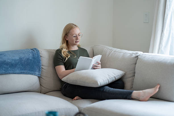 istock Woman Reading a Book on a Comfortable Sofa at Home 2218103935