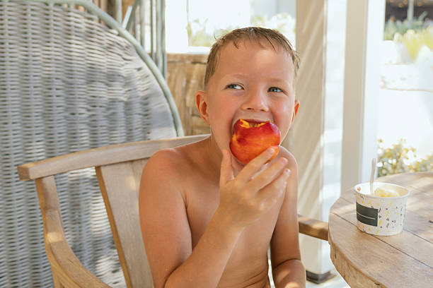 istock A six-year-old boy eats a nectarine at a beach cafe 2218105564