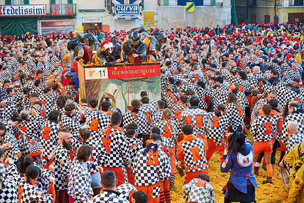 Ivrea, Italy - March 02, 2025: groups in traditional dressing take part in the Battle of the Oranges, where a teams of orange handlers on foot throw oranges (representing old weapons and stones) against aranceri of the team \