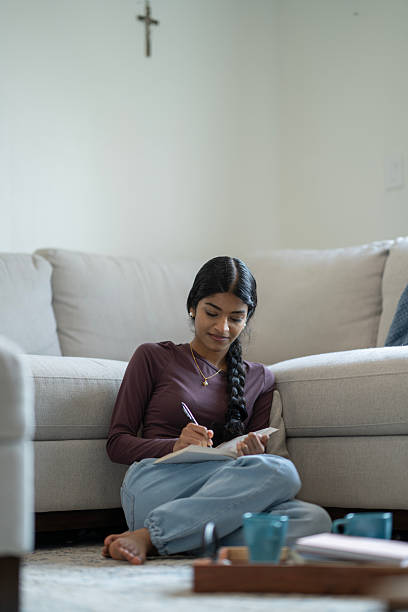 istock Young Woman Writing in a Notebook While Relaxing at Home 2218105789