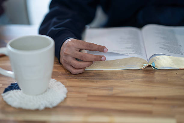 A warm scene depicting a focused individual studying the Bible, accompanied by a mug on a table.
