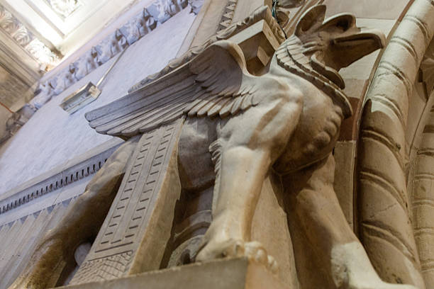 An architectural detail featuring a gryphon sculpture in a Gothic-style building, highlighting intricate stonework and artistic elements.