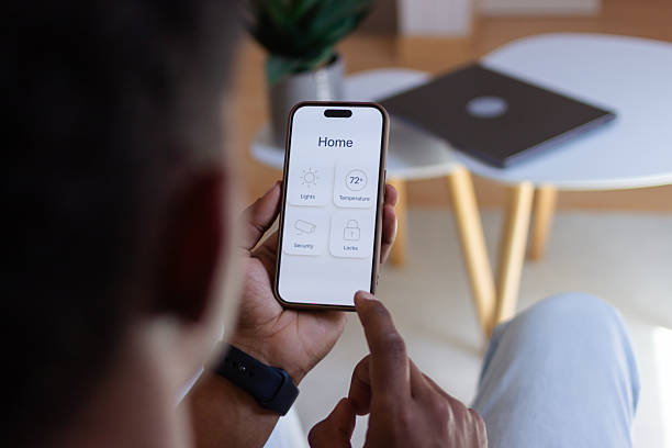 istock Man using smart home app on mobile phone to control lights, temperature, security, and locks 2218107645