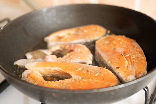 Salmon served with lemon on black pan close up