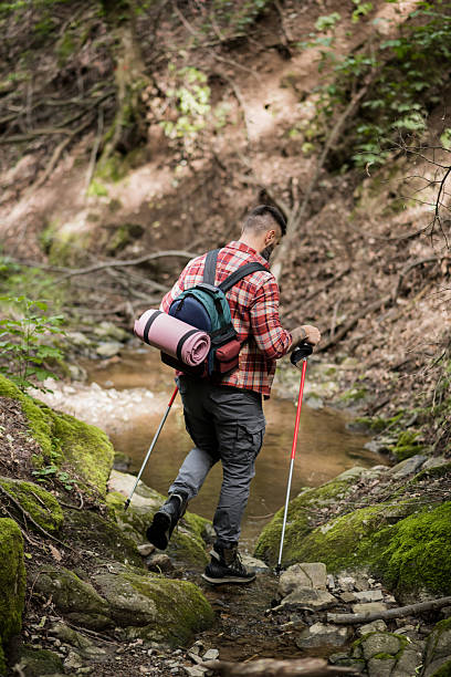 istock Man Navigates Stream on Stepping Stones 2218109520