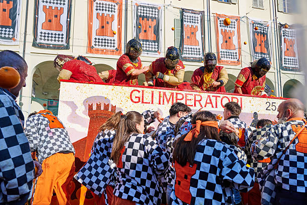 Ivrea, Italy - March 02, 2025: groups in traditional dressing take part in the Battle of the Oranges, where a teams of orange handlers on foot throw oranges (representing old weapons and stones) against aranceri of the team \