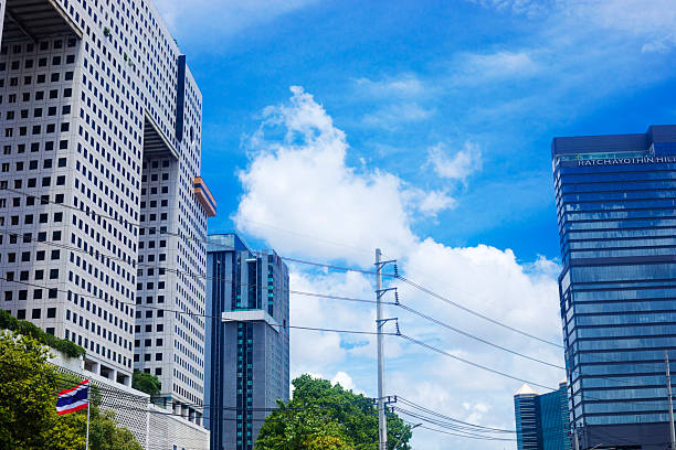 Bangkok skyline at junction Phahonyothin and Ratchadaphisek Roads in Bangkok Chatuchak in blue sky with some white clouds. At left side is elephant styled office buildign Elephant Tower. In center are office buildings. At right side is tall up hotel