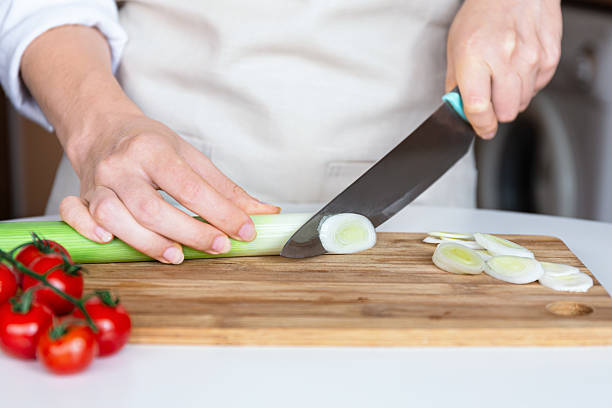 istock Slicing fresh leek on wooden board with kitchen knife 2218114788