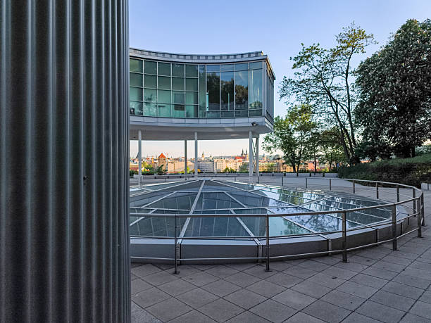 Prague, Czech republic - May 6, 2025: Modern building with glass facade overlooking the cityscape of prague at dusk, featuring a circular glass floor detail letna park