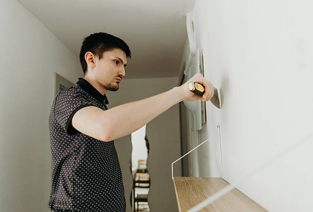 istock A young man covers a hole in the wall with putty with a spatula. 2218117110