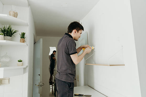 istock A young man squeezes putty from a tube into a hole in the wall. 2218117523
