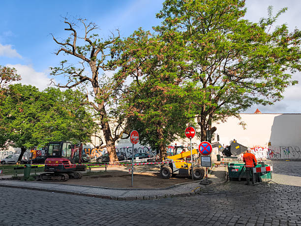 Prague, Czech republic - May 5, 2025: Construction workers preparing a park area with machinery and tools in prague, czechia, enhancing the urban landscape under a sunny summer sky