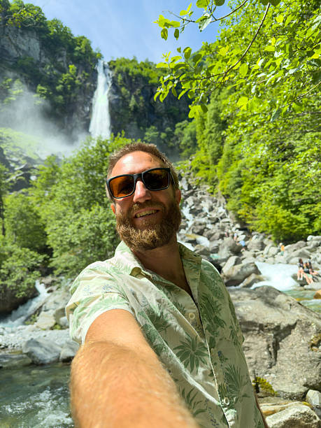 istock Smiling Man Taking a Selfie Near a Waterfall in Lush Forest 2218120536