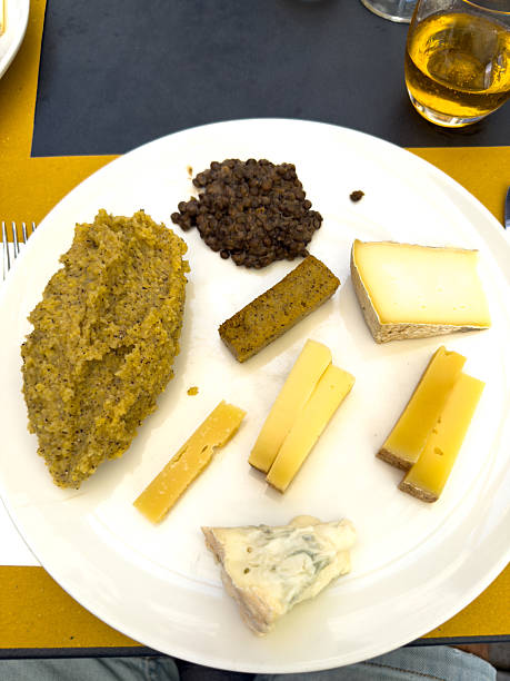 Plate of assorted cheeses with lentil serving and relish mound. Selection of gourmet cheeses with lentils. Fine dining cheese platter with diverse flavors.