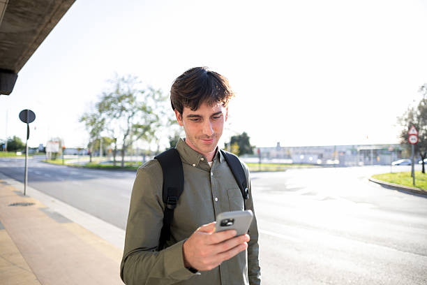 istock Businessman using smartphone while waiting for bus at bus stop 2218123465