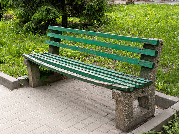 Green bench standing on the paving slabs in the park.