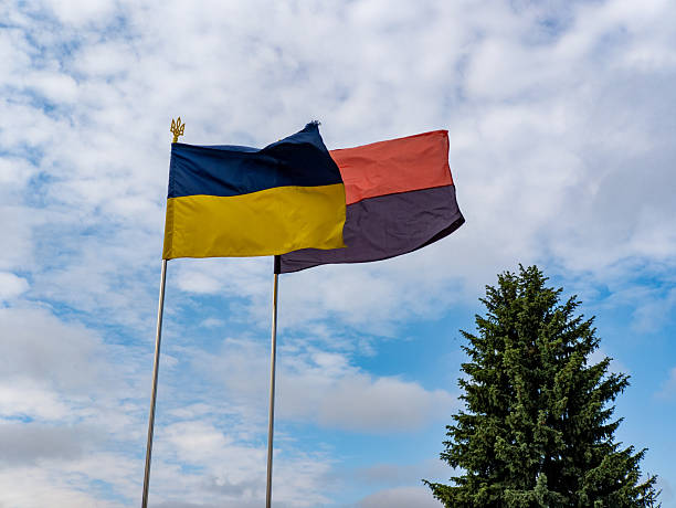 istock Two flags flying in the wind against a cloudy blue sky, Ukrainian flag 2218126330