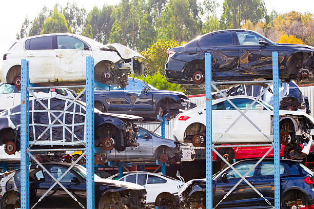 Scrapping , car dismantling. Wrecked car junkyard, ruined cars stacked, forest in the background, environmental issues. Galicia, Spain.