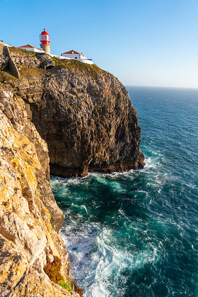 istock Lighthouse atop a rugged cliff with crashing waves 2218129786