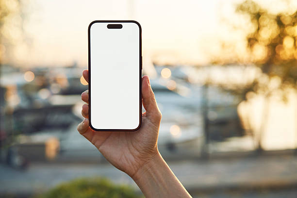 istock Young woman showing mobile phone blank white screen on Marina Background 2218131105